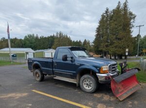 Pickup truck with snowplow attachment in parking lot.