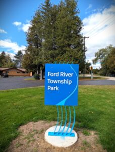 Ford River Township Park sign with trees background.
